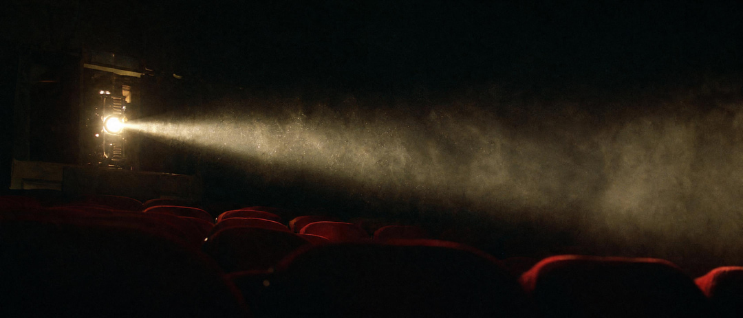 A cinema projector beam through haze over an empty theatre